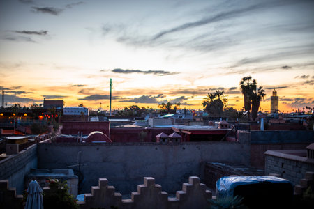 yellow and orange sunset between the roofs of the houses and palm trees in Marrakech in Morocco