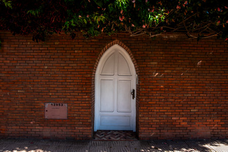 white wooden door with pointed arch on ashlar wall and green hedgeの写真素材