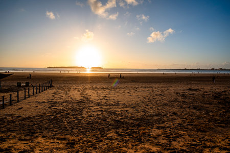 photography of the sunset on the sea in the immense beaches of Essaouira in Morocco with the sun setting on the fiery sky and reflections on the seaの写真素材