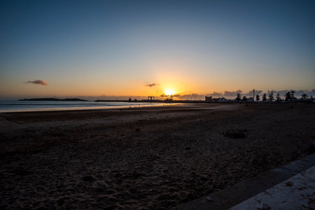 photography of the sunset on the sea in the immense beaches of Essaouira in Morocco with the sun setting on the fiery sky and reflections on the seaの写真素材
