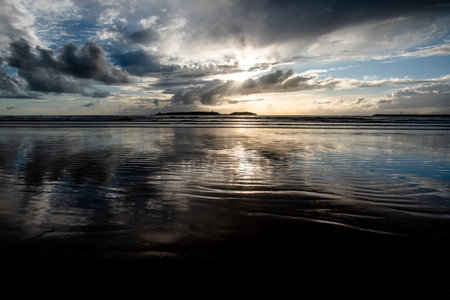Sunset on the vast beaches of Essaouira with blue skies, white clouds and waves crashing on the...