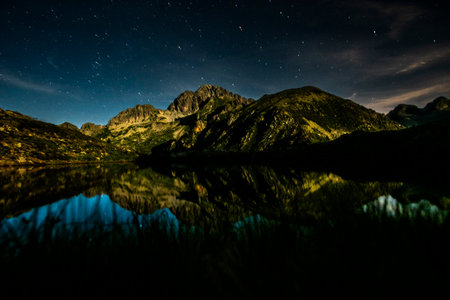 Starry night over the Lagorai mountains, Trentino, Italy. Alpine lake perfectly reflecting rocky peaks and constellations, peaceful and untouched mountain wilderness.の写真素材