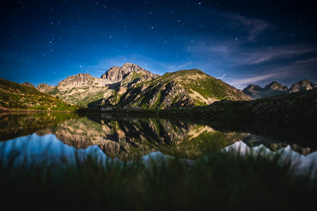 Starry night over the Lagorai mountains, Trentino, Italy. Alpine lake reflecting rugged peaks and a clear Milky Way sky, serene wilderness under starlightの写真素材