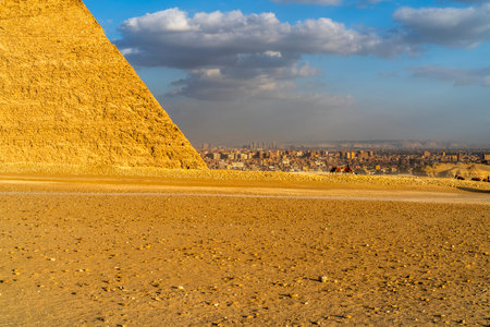 View of the Great Pyramid with Cairo city skyline in the background, Egypt, showing ancient...