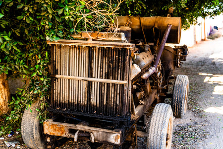 Rusty industrial generator abandoned along a quiet street in Giza, Egypt, surrounded by vegetation, showing urban decay, infrastructure aging, and environmental contrast.の写真素材