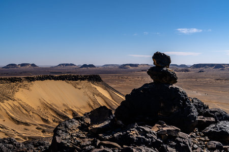 Stacked basalt stones overlooking a wide desert valley in Egypt's Black Desert near Giza, conveying...