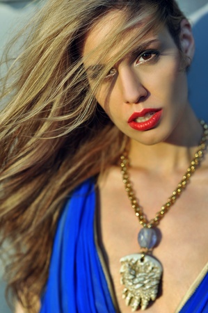 Closeup portrair of fashion model with full hair and red lips,  posing sexy and wearing long blue evening dress and fashion acessoriesの写真素材