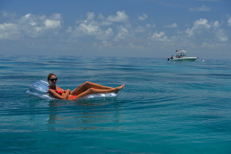 Woman in red bikini on floating device at open waters of carribbeanの写真素材
