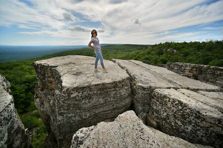 Young woman posing at the edge of rock at Minnewaska State Park Reserve Upstate NY during summer...