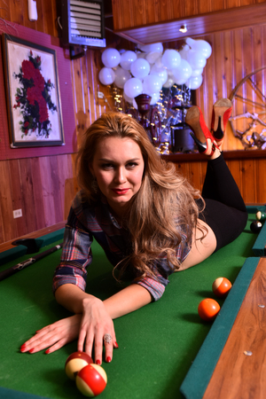 Young woman posing sexy in front of billiard pool table wearing leggins, shirt and red shoes