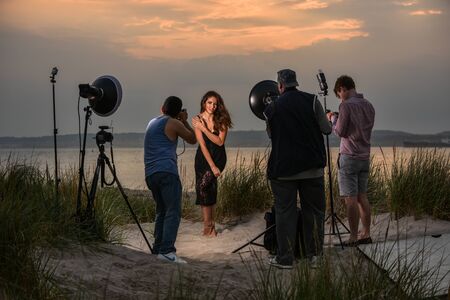 Group of photographers shooting model at the beach location on sunset time