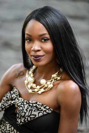 Outdoor portrait of beautiful young African American woman wearing sexy dress and jewelry.の写真素材