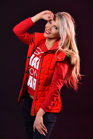 Studio fashion shot of beautiful young blond woman wearing red jacket.の写真素材