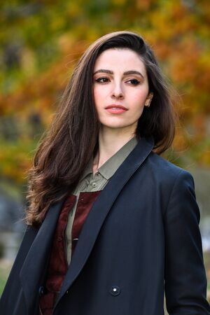 Romantic young woman in autumn scenery.  Blurry foliage on the background.
