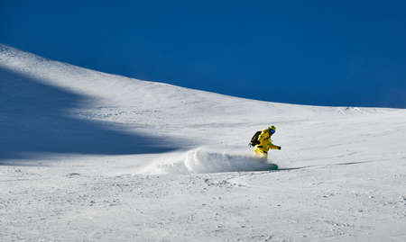 Man wearing yellow suit snowboarding down at extreame double diamond area at Emperial bowl .Extreme winter sports. Action shot. Breckenridge, COの写真素材