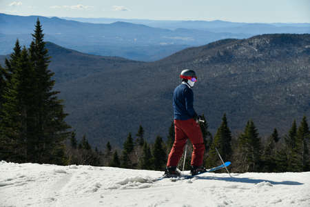 Skier standing on the edge of mountain at Stowe ski resort observing way down the slopes.