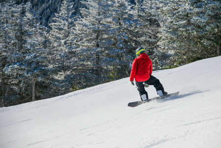 Dynamic photo of snowboarder in bright jacket downhill. Enjoying winter vacation snowboarding in the mountains on fresh powder snow slopes.の写真素材