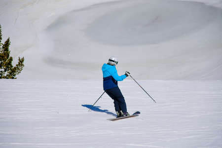 Skiing downhill on a beautiful sunny day at Snowbasin Ski Resort, Utah. Spring conditions in mountains, April month.の写真素材