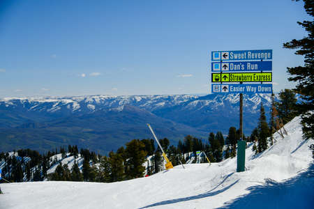 Trail sign at Snowbasin Ski Resort, Utah. Top view to the valley with mountains range during early spring weather conditions.の写真素材
