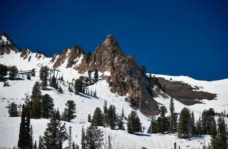 Beautiful landscape at Snowbasin Ski Resort, Utah. Snow slopes, rocky mountains and trees on a sunny...