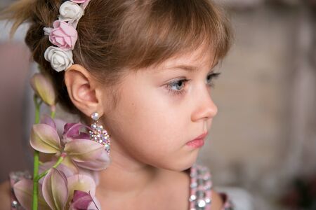 Little girl lady in pink dress and hat sits among magic flowersの写真素材