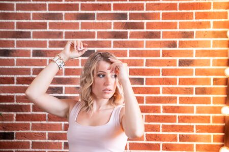 Beautiful young swag style dressed girl in short jeans at textured red bricks wall backgroundの写真素材