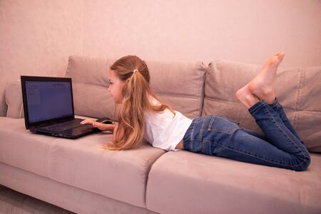 Happy little girl at home working with a laptop, computerの写真素材