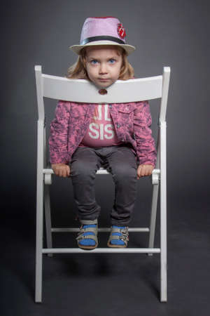 A little girl in a hat gray background. In a pink shirt and grey pants. the childhood passes cheerfullyのeditorial素材