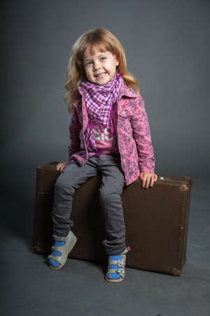 Little girl sits on large suitcase bagのeditorial素材