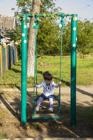 Little girl swinging. Happy laughter baby girl on swingの写真素材