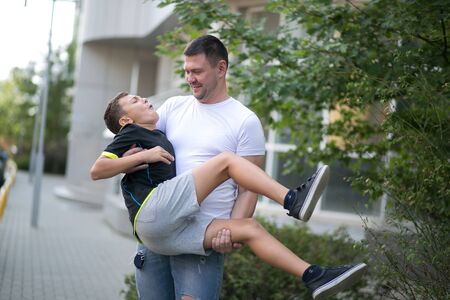Father and son walking outdoors together in summer on the street