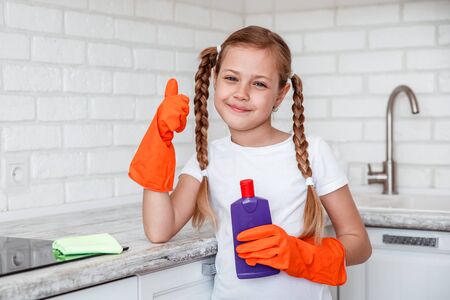 Cleaning . little girl cleans kitchen stove in beautiful kitchenの写真素材