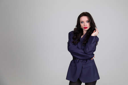 Dressed in men's style. Beautiful girl men 's jacket on gray background. Portraitの写真素材