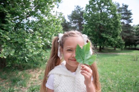 Cute young child in nature holding a leaf over eyeの写真素材