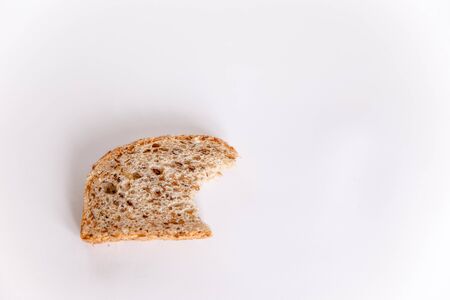 A bitten piece of useful bread with cereals on a white background