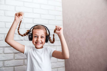 Little girl in big headphones listens to music and laughs. Copy spaceの写真素材