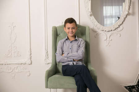 Boy sits in a beautiful chair. photographic studio