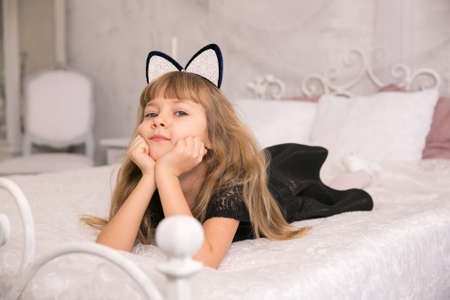 Girl with ears cats lie on bedの写真素材