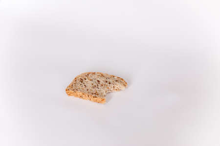 A bitten piece of useful bread with cereals on a white background