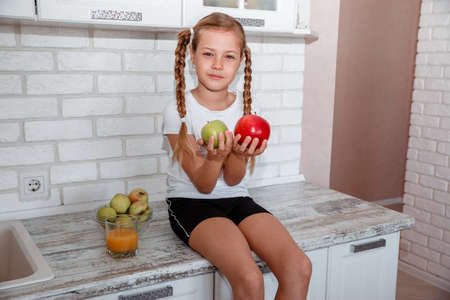 Cute little girl with apples in the kitchenの写真素材