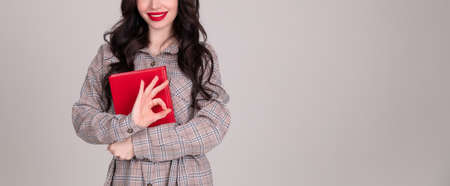 Young modern woman of European appearance holds a notebook to take notes. Girl student. Near person...