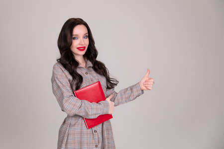 Beautiful girl student business women with red notebook on white, gray background. beautiful smile. Copy spaceの写真素材
