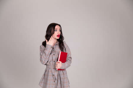 Girl student closes the palm of her mouth, stress. On Gray Background In Studio.Copy spaceの写真素材