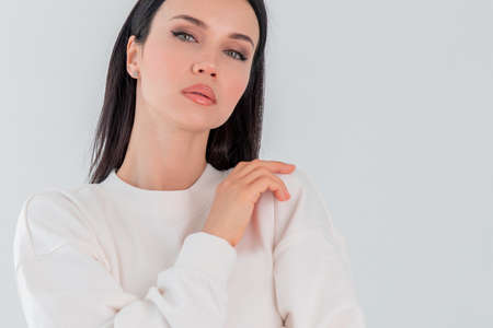 Beautiful adult girl model in white sweater hoody isolated over gray white background. Copy space