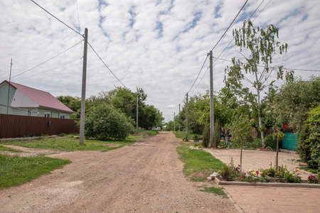 Russian village in summer. View of the village street with traditional wooden houses and old power line along the street. street in Russia. summer. road. villageの写真素材