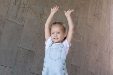 girl is 5 years old. little girl raises her hands up.の写真素材