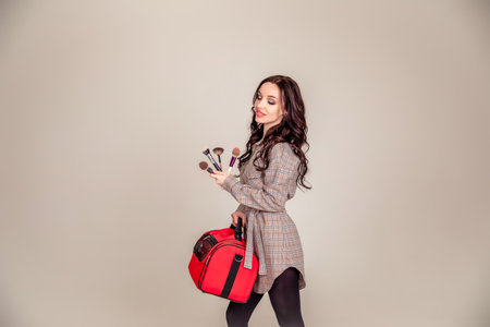 portrait of a beautiful young brunette with long hair. girl makeup artist holds makeup brushes in her hands. Beauty club concept. Copy spaceの写真素材