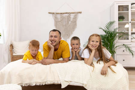 Dad with the kids on the bed. dad stayed at home with children. Quarantine with children.の写真素材
