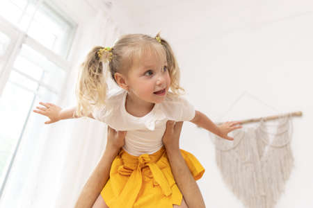 Dad playing with his baby daughter, he holds her in his arms. Dad's holding her daughter in her arms. the child flies in daddy's arms.の写真素材