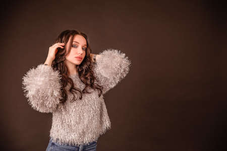 portrait beautiful girl poses on a black gray background. lady in jeans and gray fluffy sweaterの写真素材
